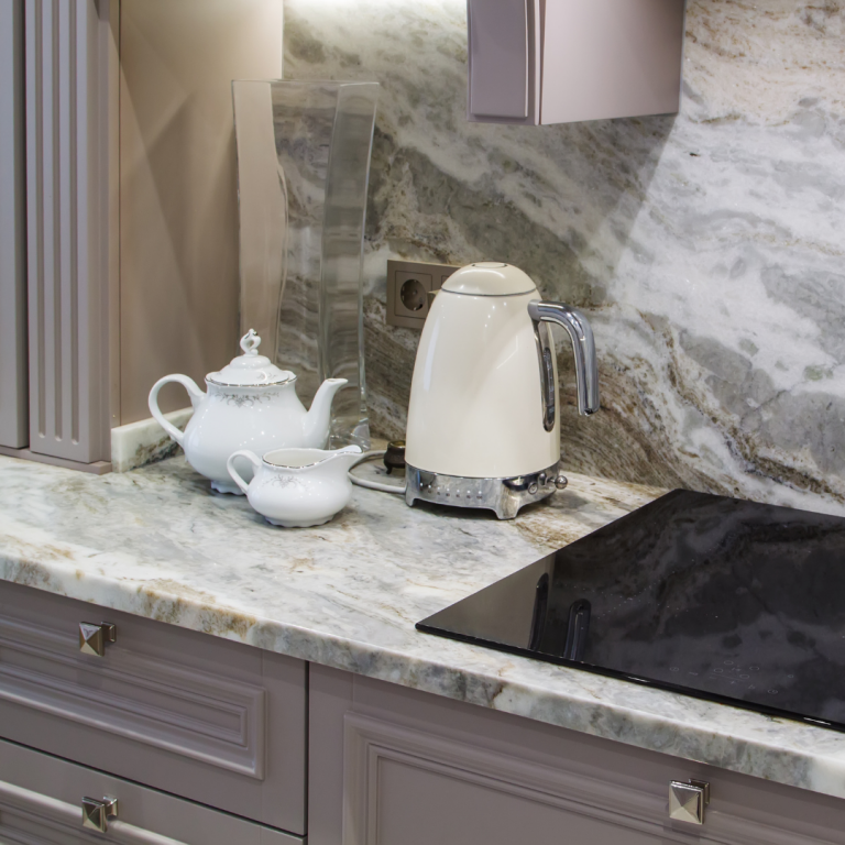 Kitchen countertop made of quartz with a kettle, teapot and milk jug in shot. To the right is a conductive cooktop